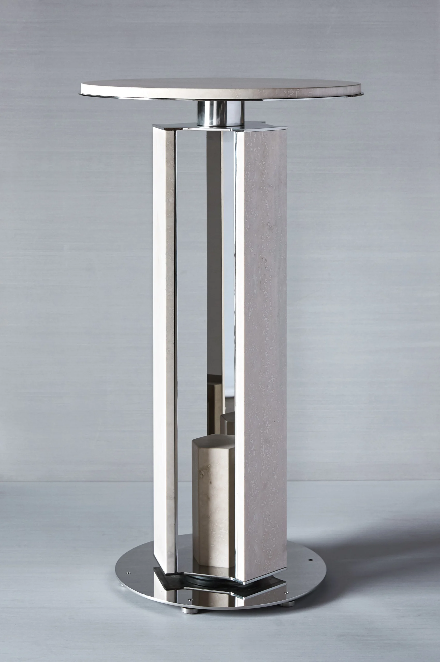 Modern metal pedestal table with a Travertine and Stainless Steel finish